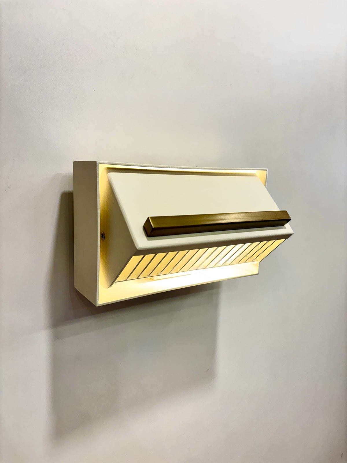 MURAFA mid-century wall sconce in cream and matte brass, lit, angled view