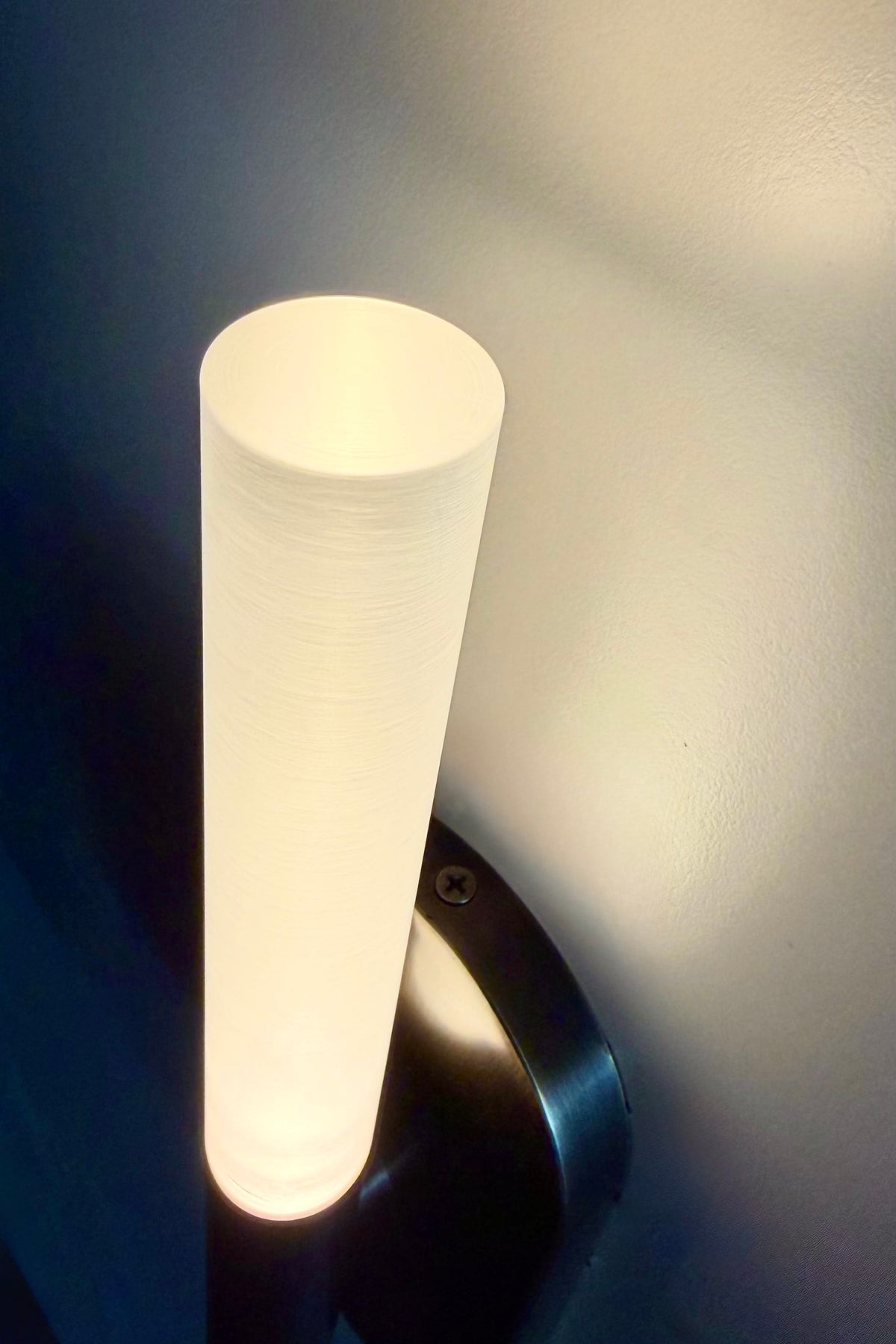 Close-up of the glowing frosted plexiglass tube of the MUSALA wall sconce